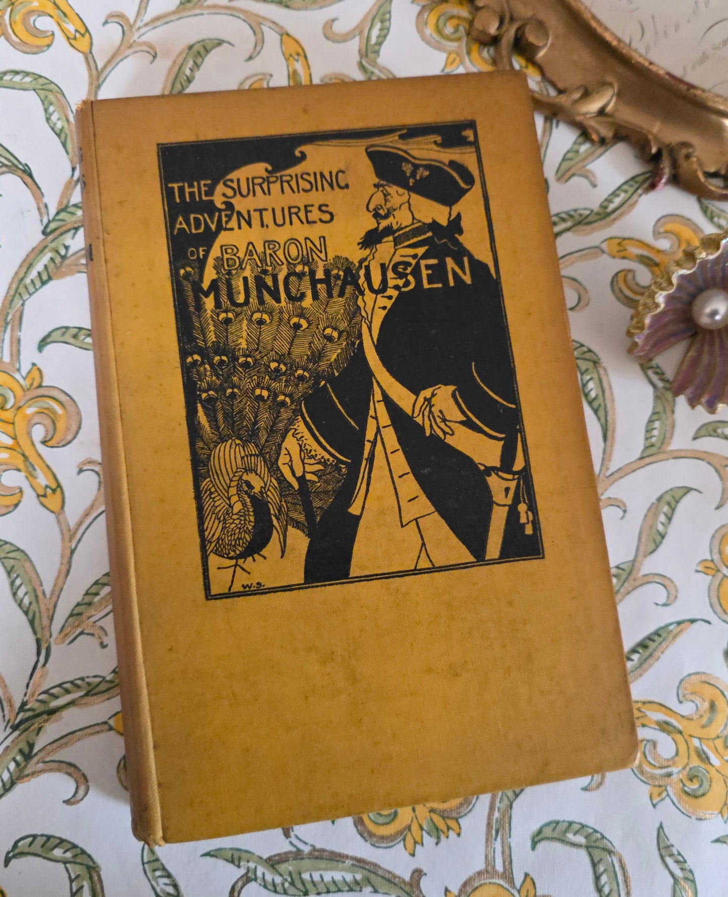 Yellow and vintage book titled 'The Surprising Adventures of Baron Munchausen' on a decorative background