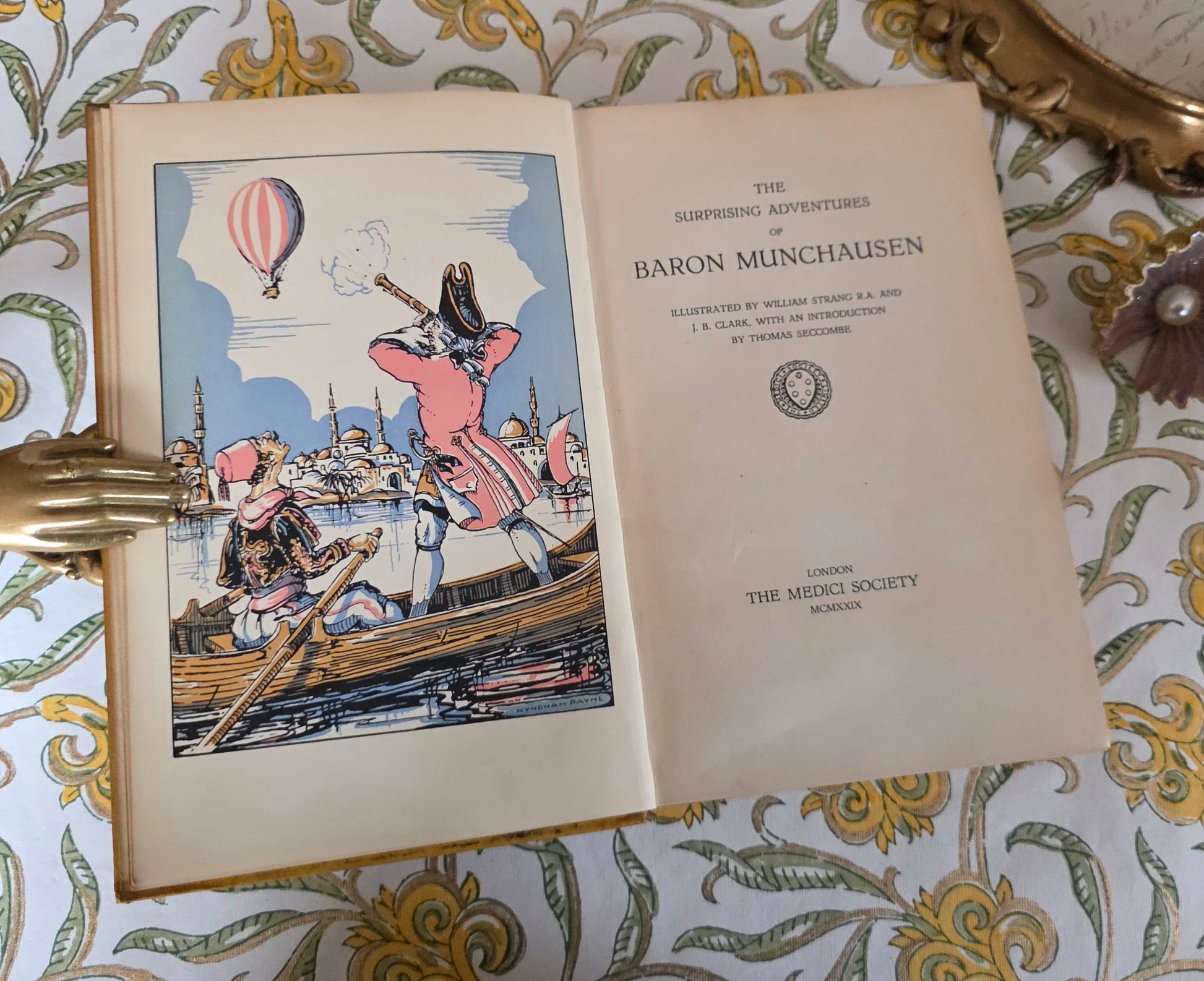 Open book titled 'The Surprising Adventures of Baron Munchausen' showing title page, The Medici Society and the colour frontispiece 