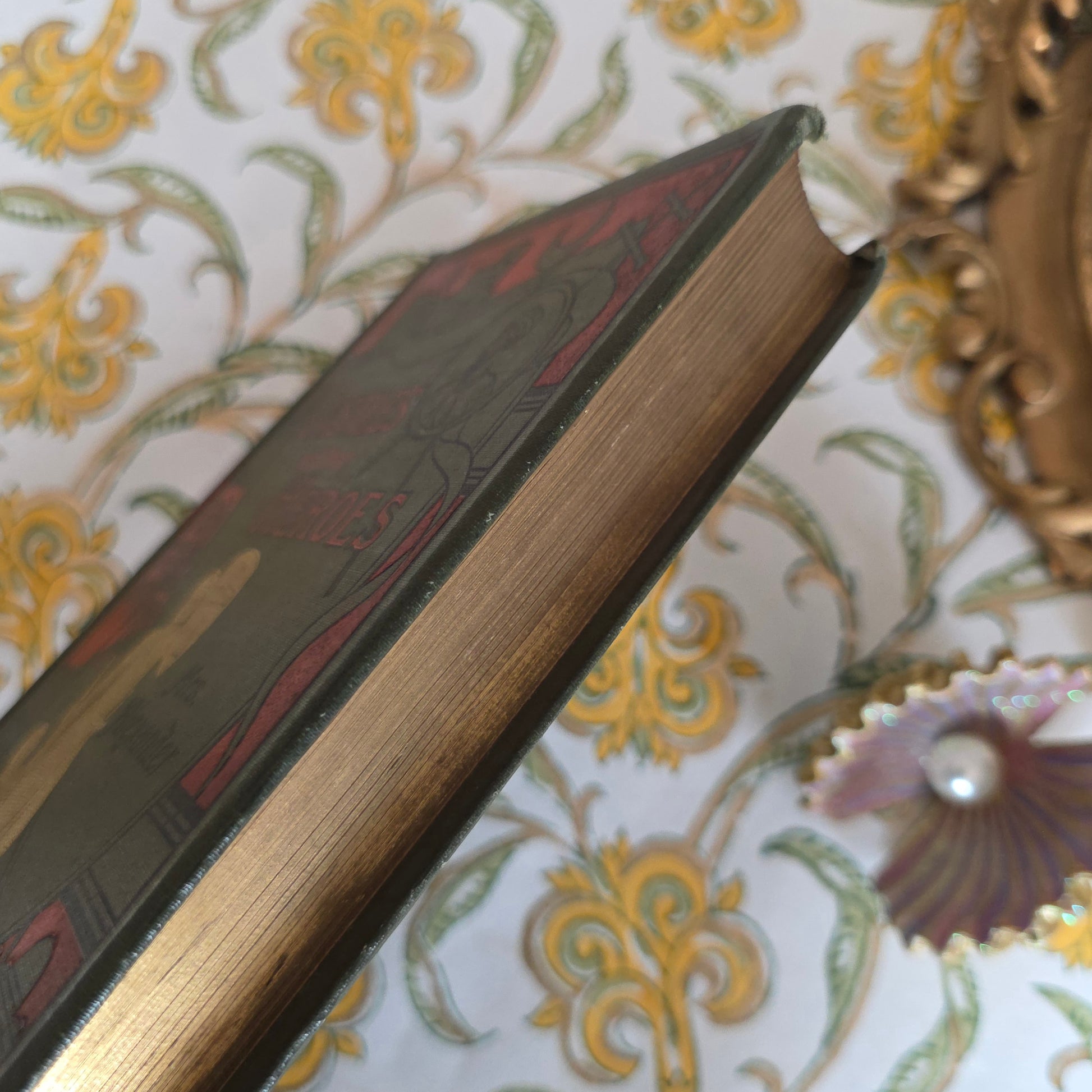 Vintage book, with gilt edges on a decorative surface with intricate patterns