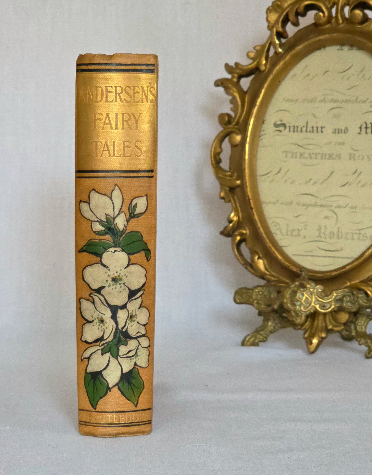 Antique book spine in light brown cloth, floral decoration and gilt titles saying Andersen's Fairy Tales.