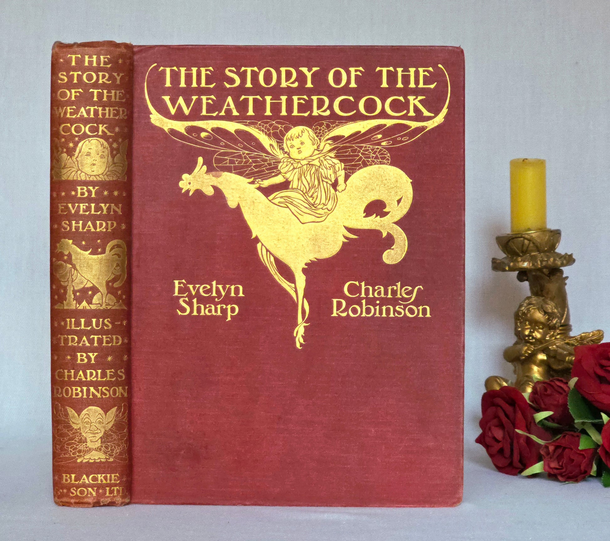 Antique book in red cloth with gilt titles saying 'The Story of the Weathercock' by Evelyn Sharp
