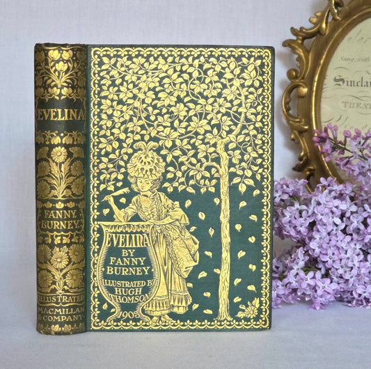 Vintage book titled 'Evelina' by Fanny Burney with gold illustrations on a light gray background.