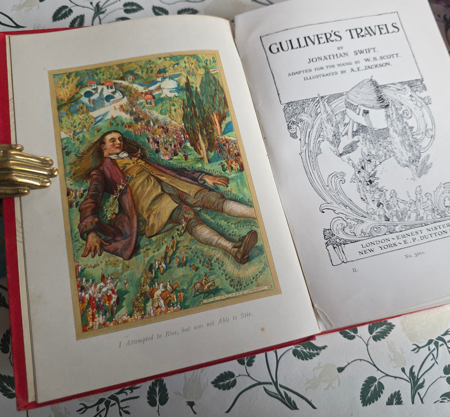 Open book with frontispiece illustration and title page of 'Gulliver's Travels' on a decorative surface.