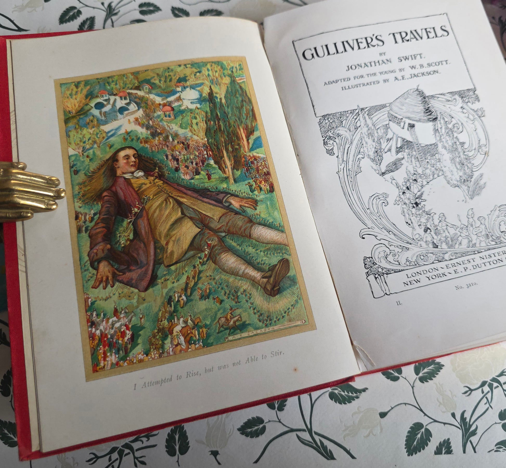 Open book with frontispiece illustration and title page of 'Gulliver's Travels' on a decorative surface.