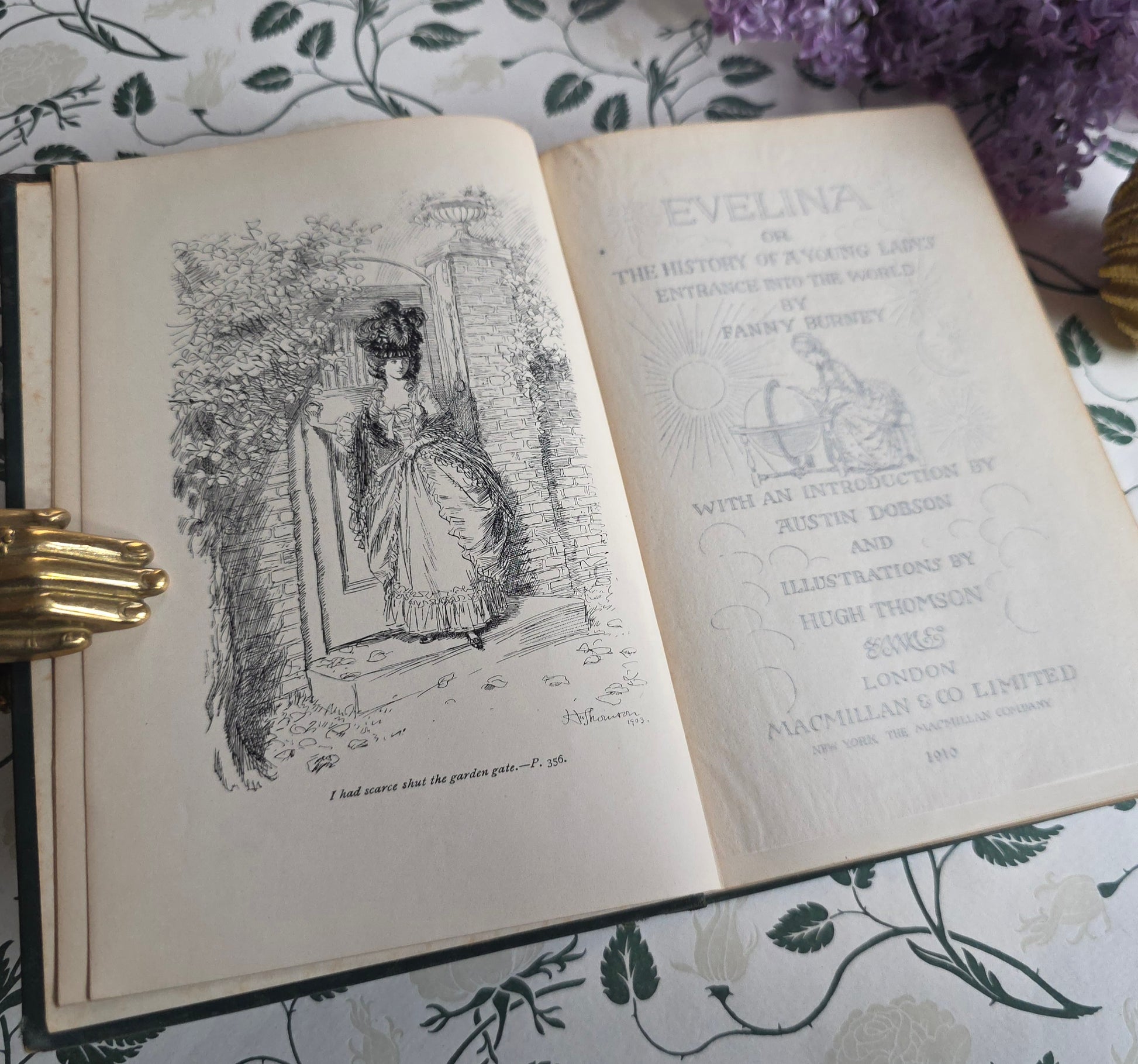 Open antique book titled 'Evelina' showing title page and frontispiece with illustrations on a floral-patterned surface