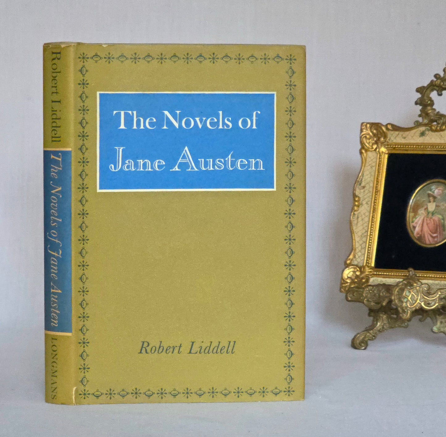 Book titled 'The Novels of Jane Austen' by Robert Liddell on a white surface with a decorative frame in the background.