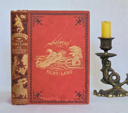 Antique book in red cloth with black and gold decoration saying 'Whispers in Fairyland' by Knatchbull-Hugesson