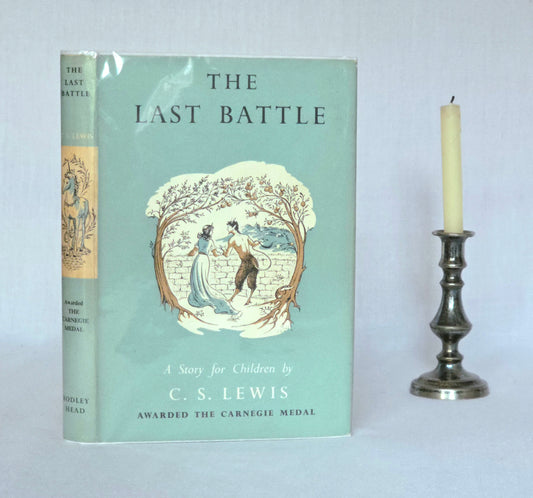 1st edition book titled 'The Last Battle' by C.S. Lewis with a candle on a plain background