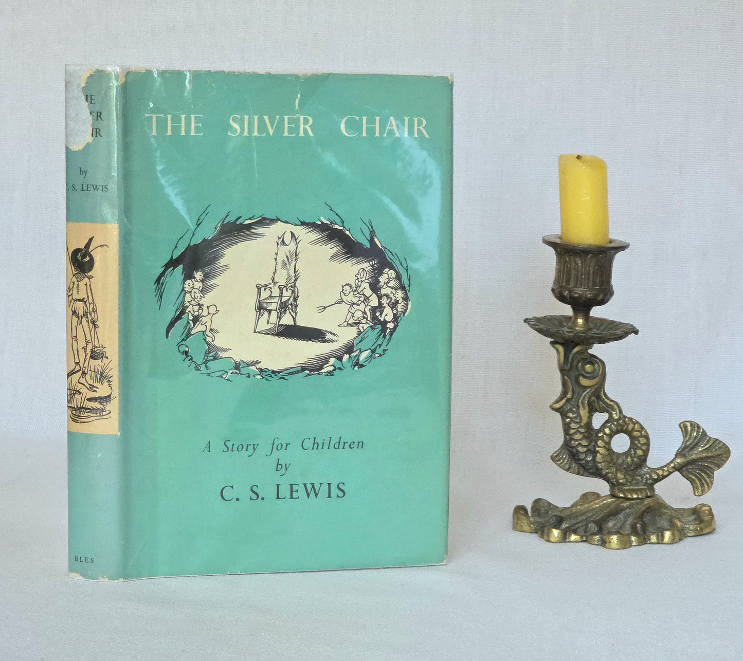 1st edition book titled 'The Silver Chair' by C.S. Lewis with a candle and decorative candlestick on a light background